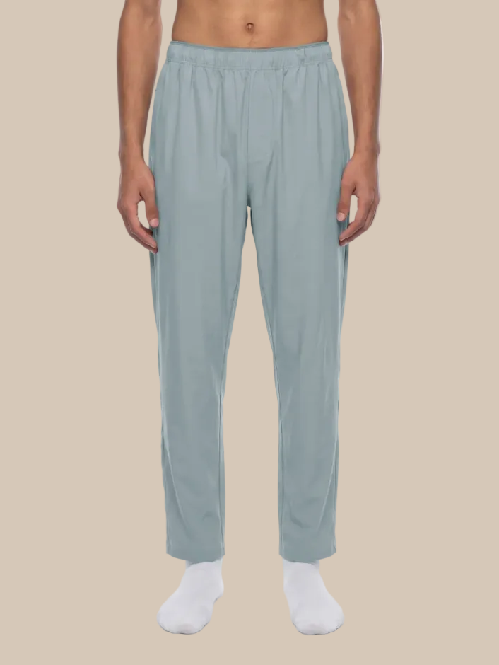 Person wearing gray blue track pants on a beige background
