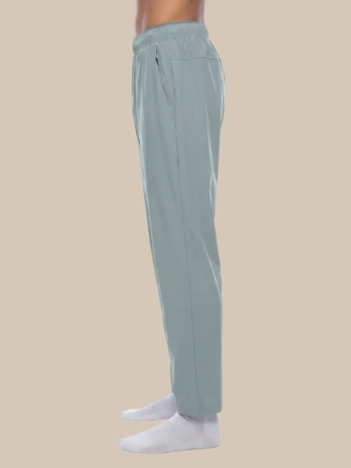 Blue gray track pants worn by a person on a beige background