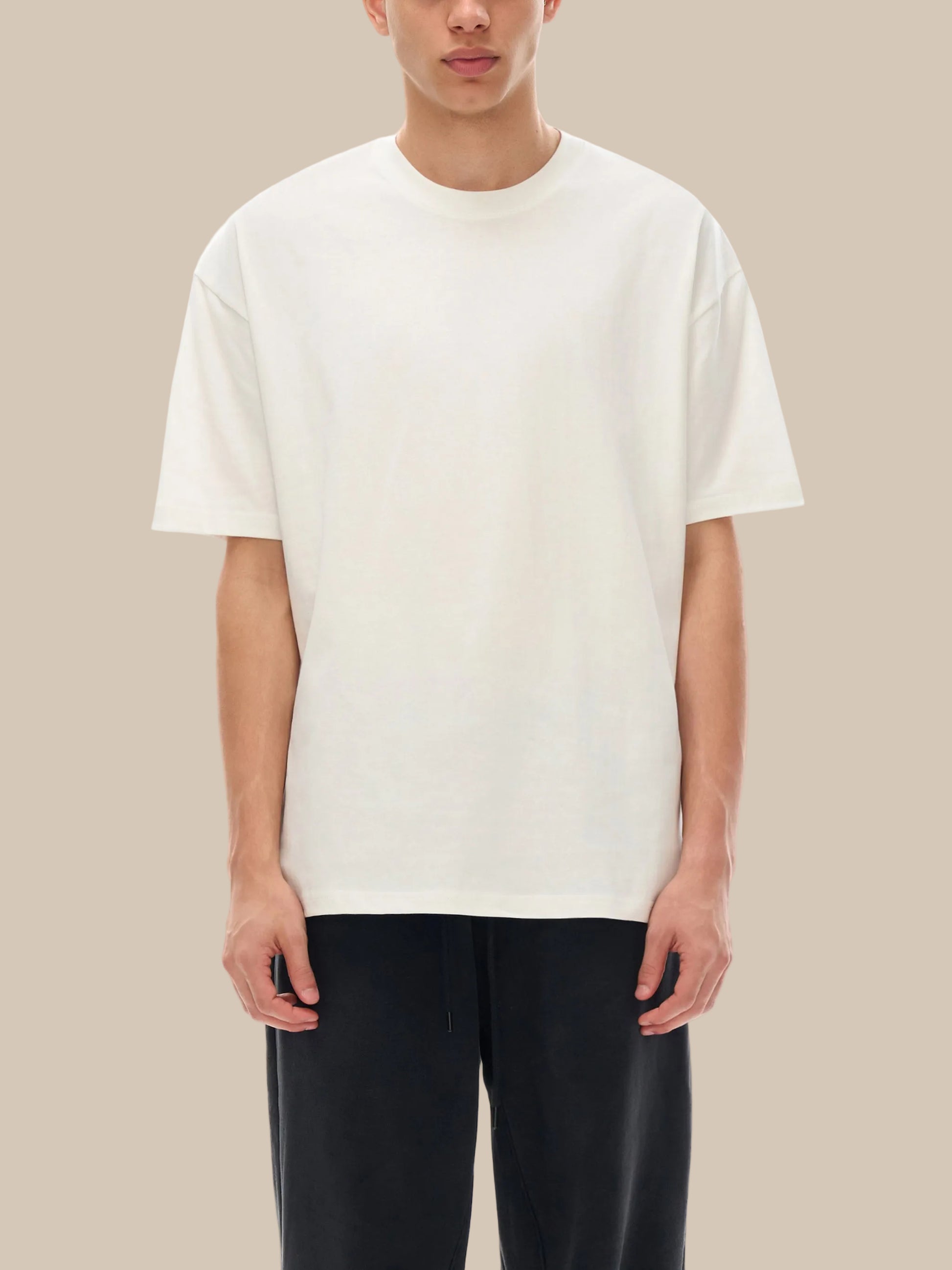 Person wearing a plain white t-shirt and black pants on a white background
