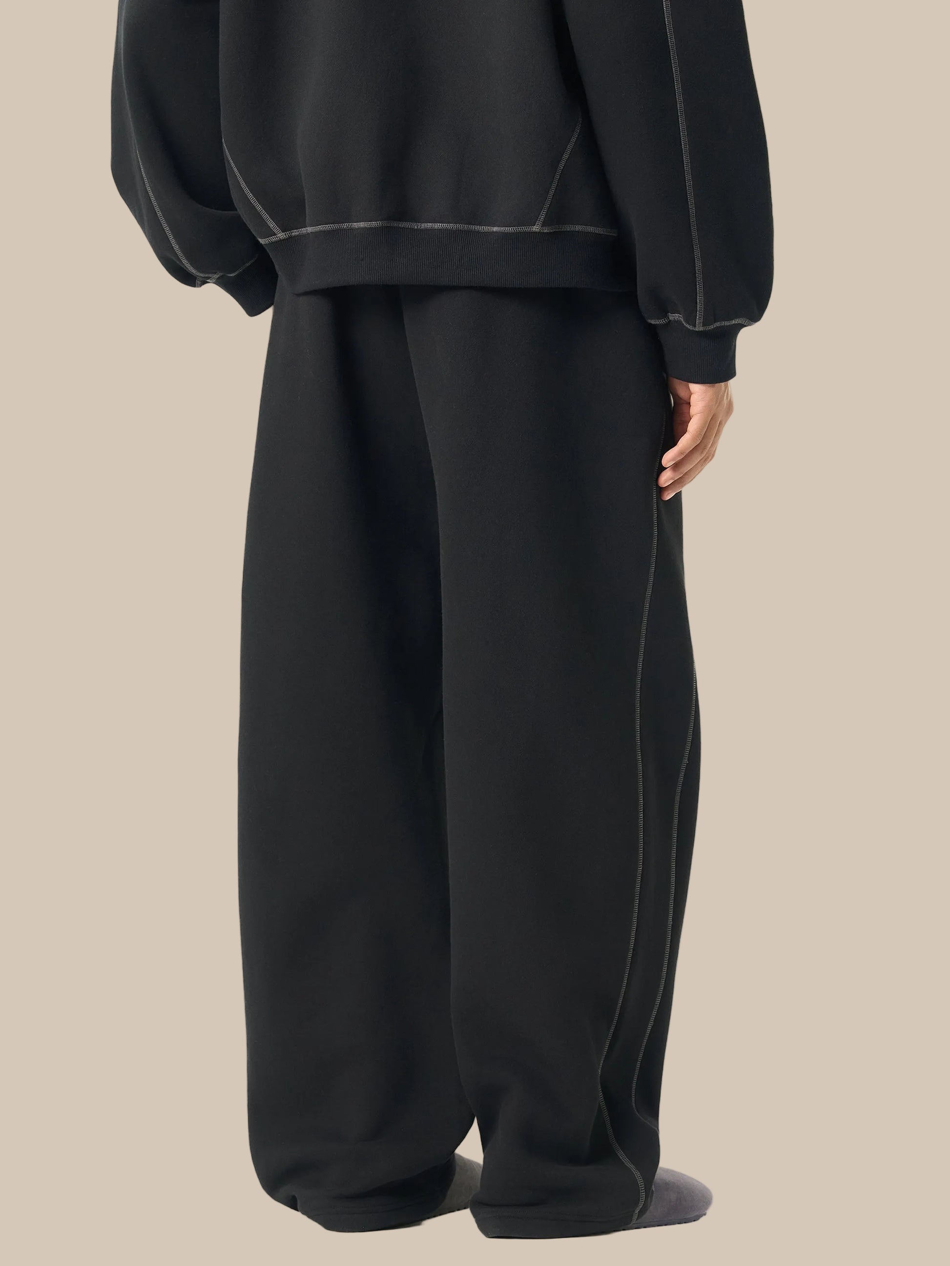 Person wearing a black outfit with wide-leg pants on a white background