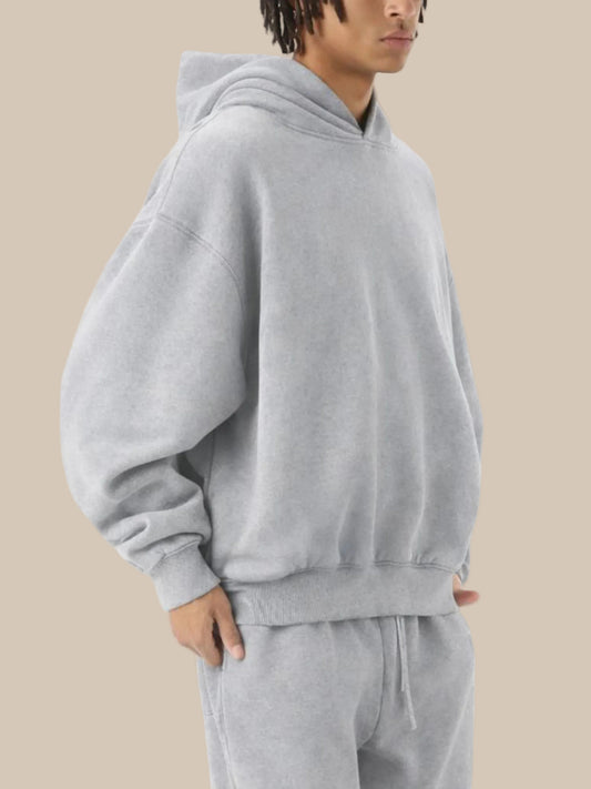 Person wearing a gray hoodie and pants on a white background