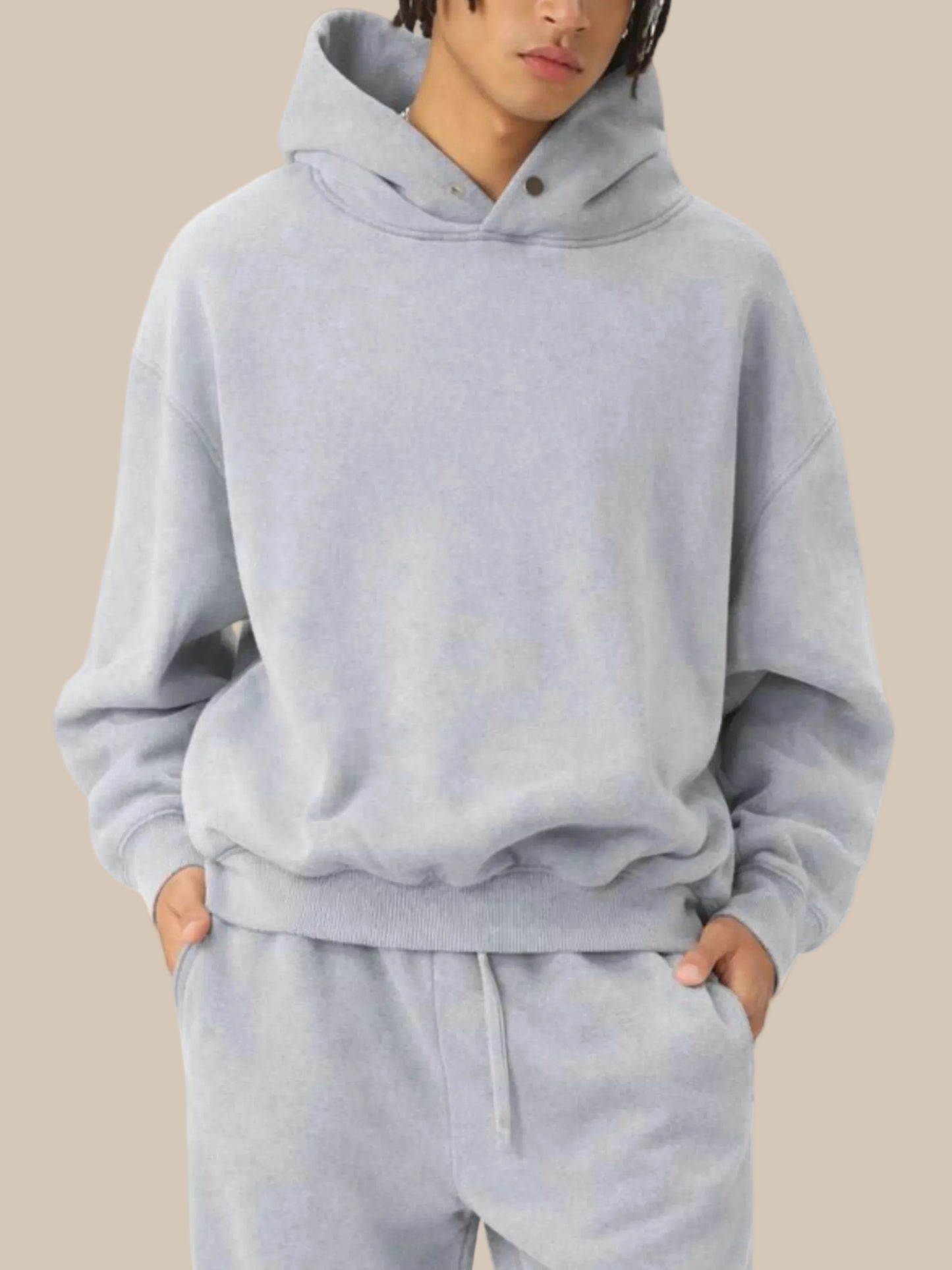 Person wearing a gray hoodie and pants set on a white background