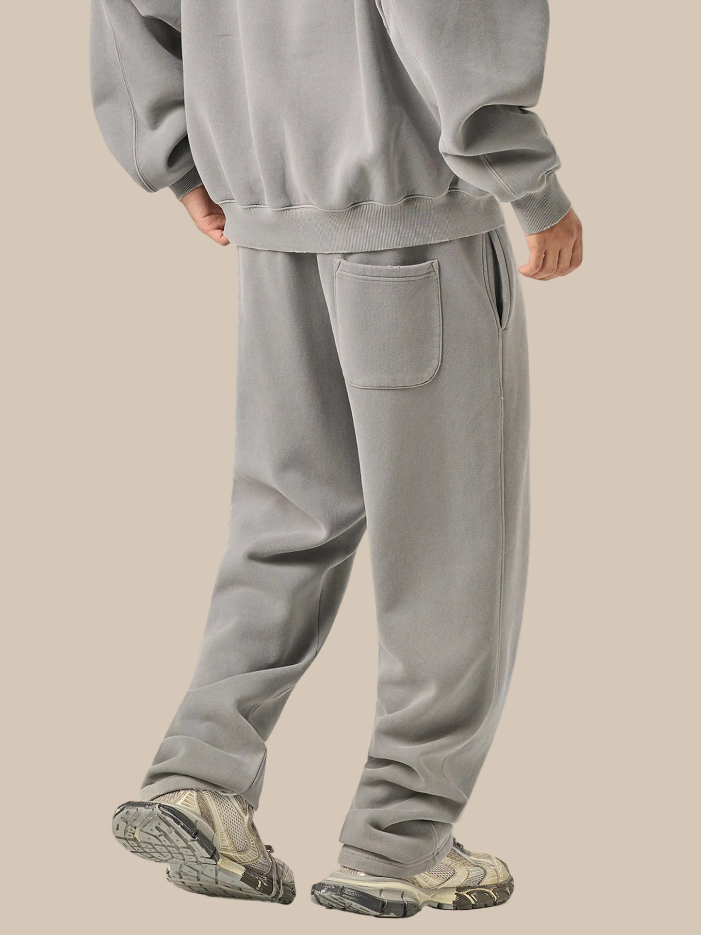 Person wearing a gray tracksuit on a white background