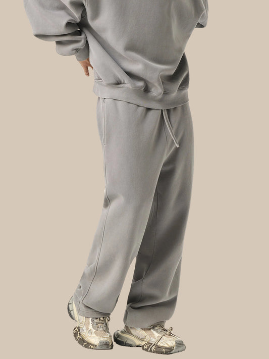 Person wearing a gray tracksuit with camouflage shoes on a white background