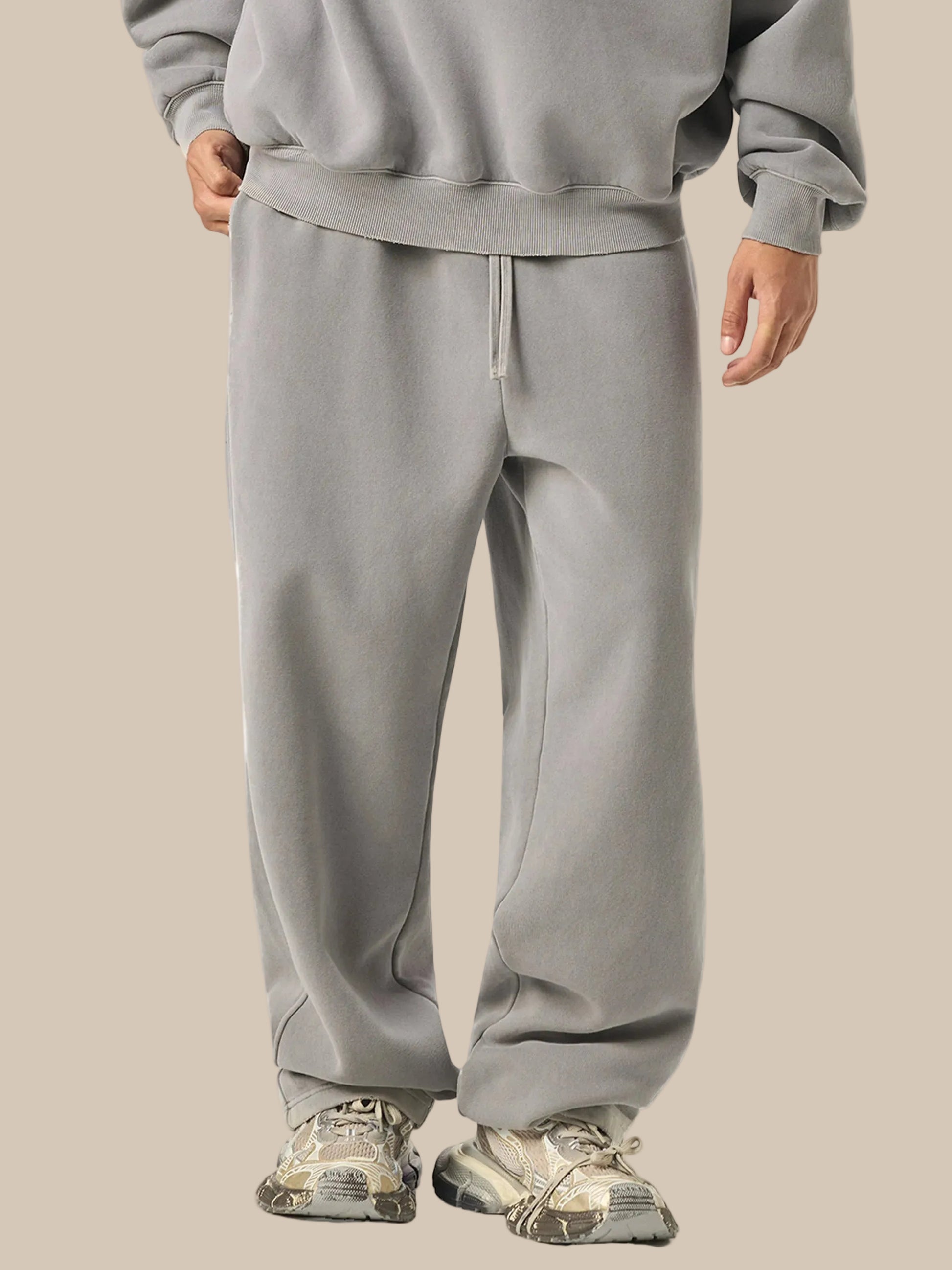 Person wearing a gray tracksuit with hiking shoes on a white background