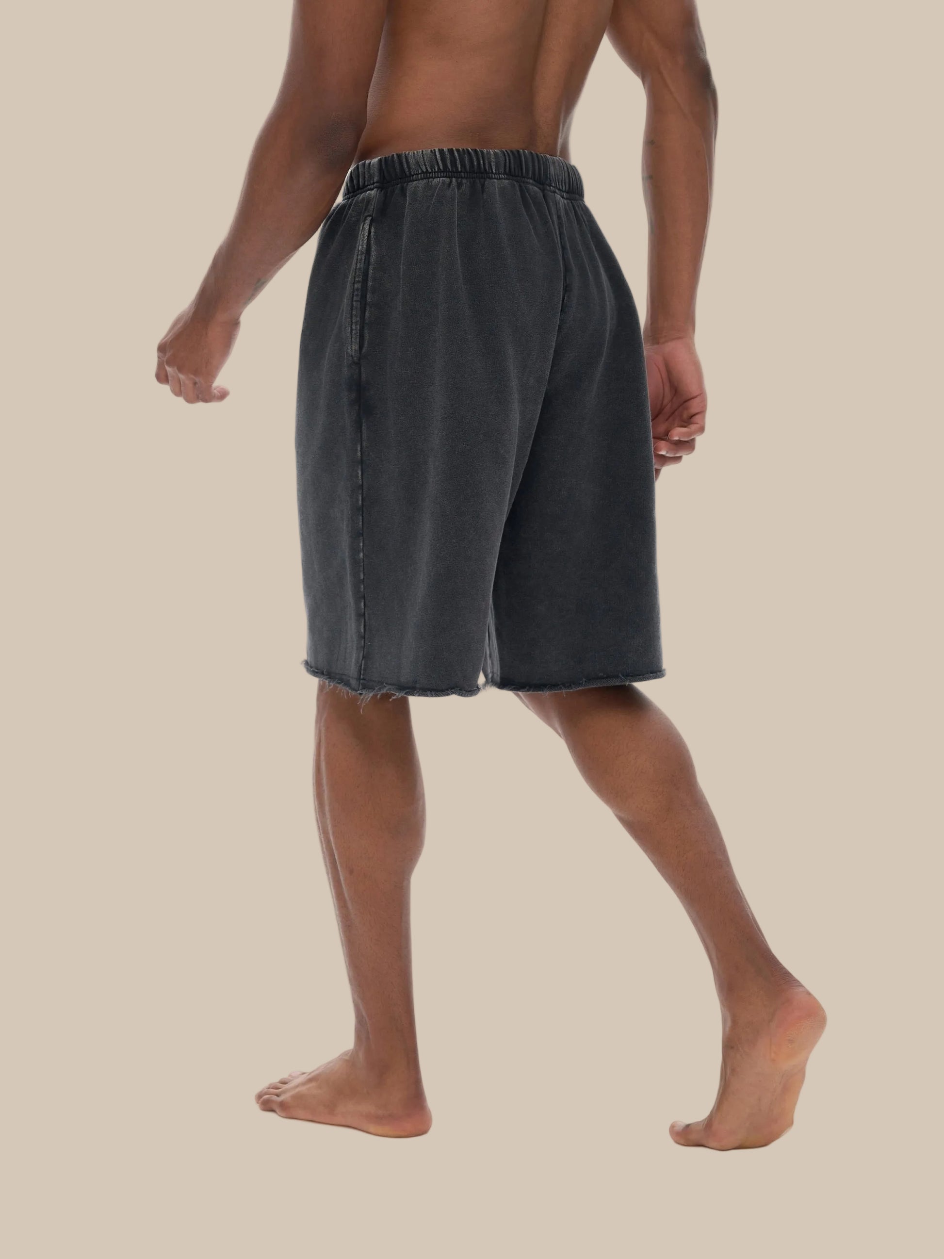 Person wearing black shorts on a beige background