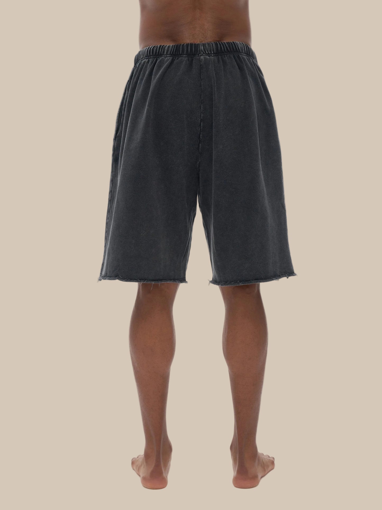 Person wearing black shorts on a beige background