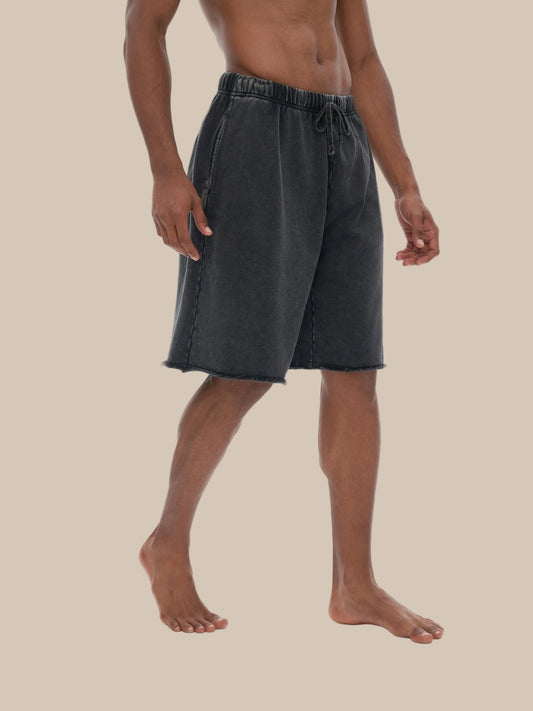 a man wearing black future-homme acid wash shorts on a beige background. 