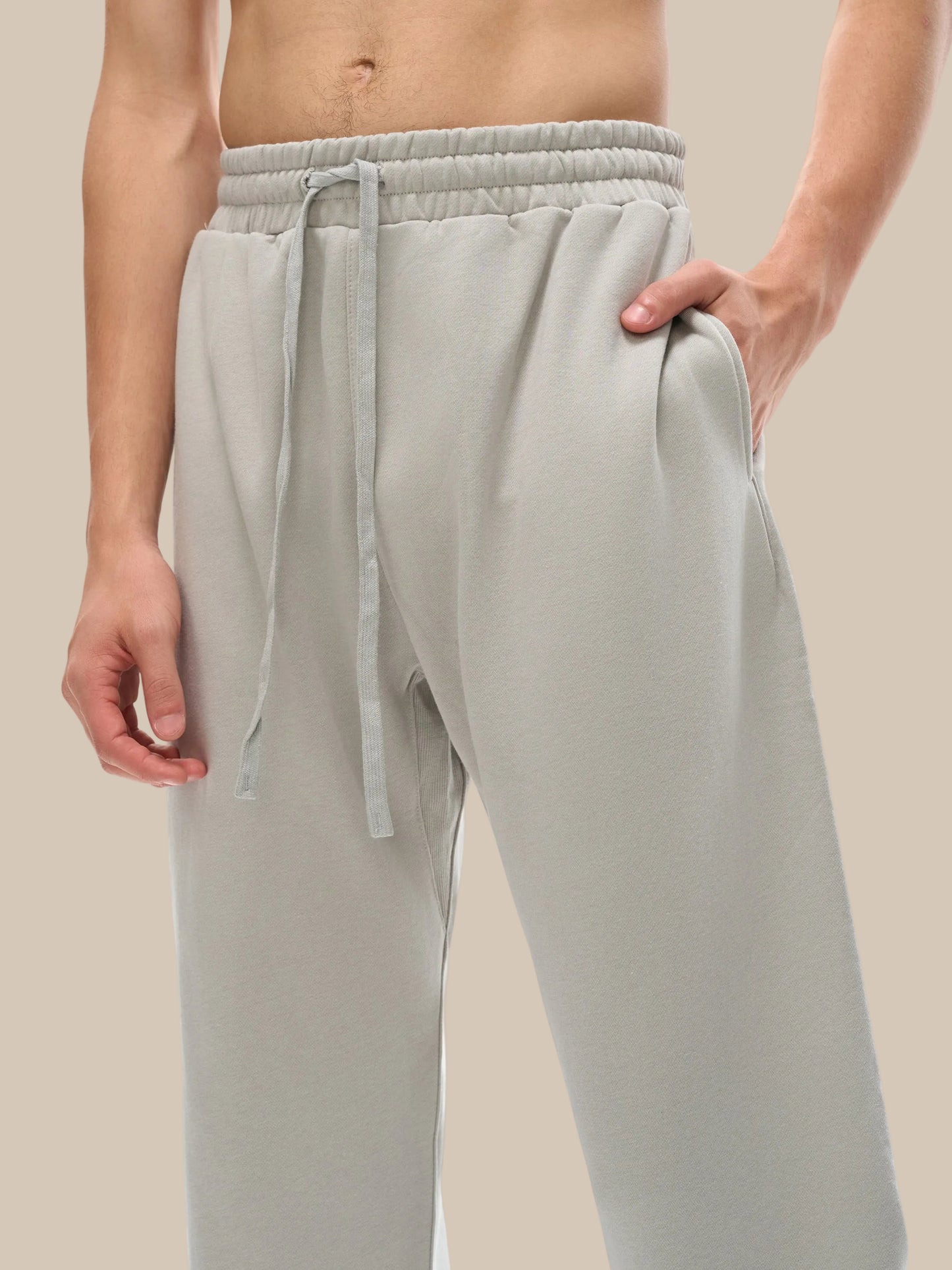 Light gray sweatpants worn by a person on a white background