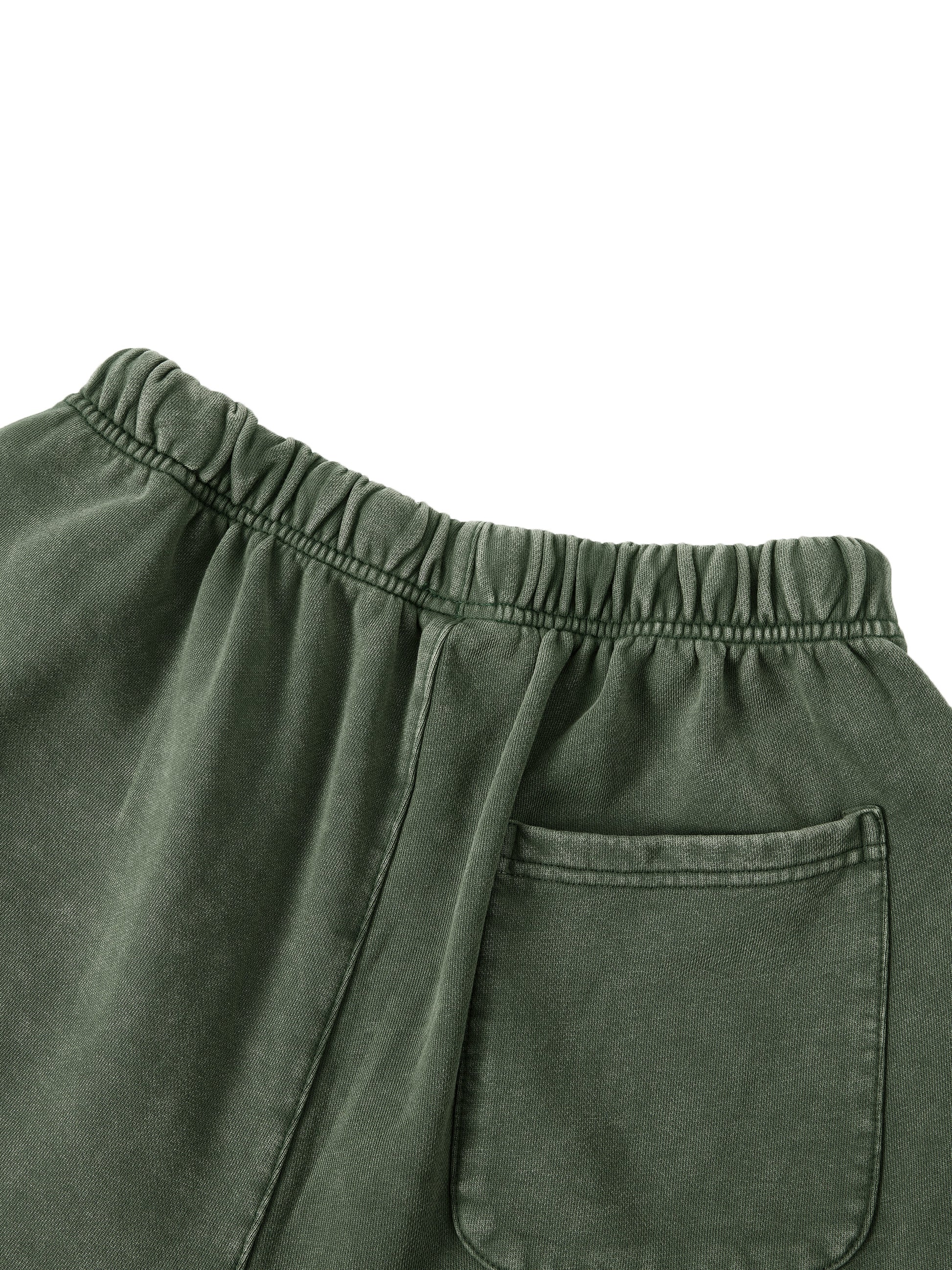 Close-up of green pants with an elastic waistband and pocket on a white background