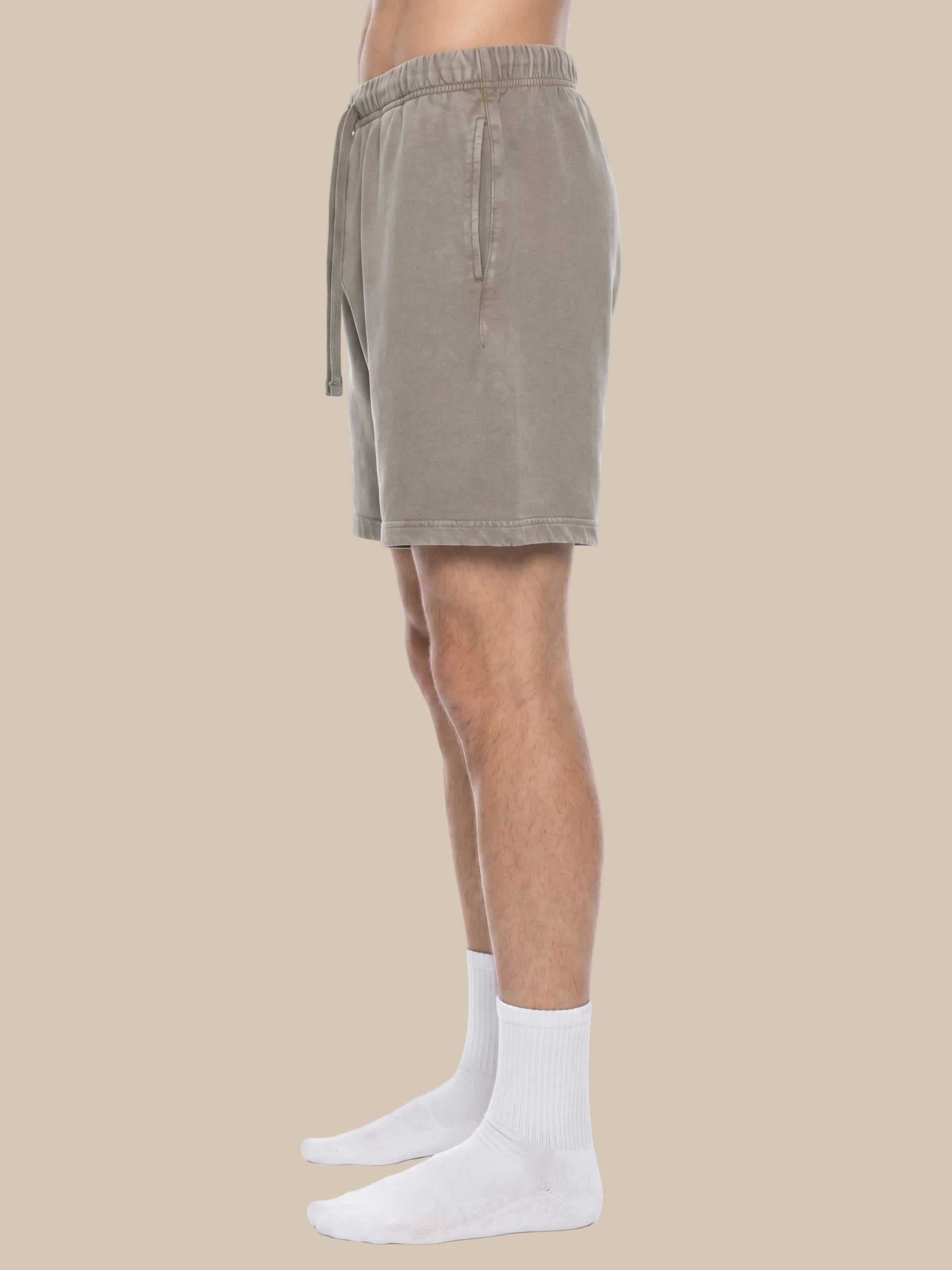 Person wearing beige future-homme shorts and white socks on a beige background