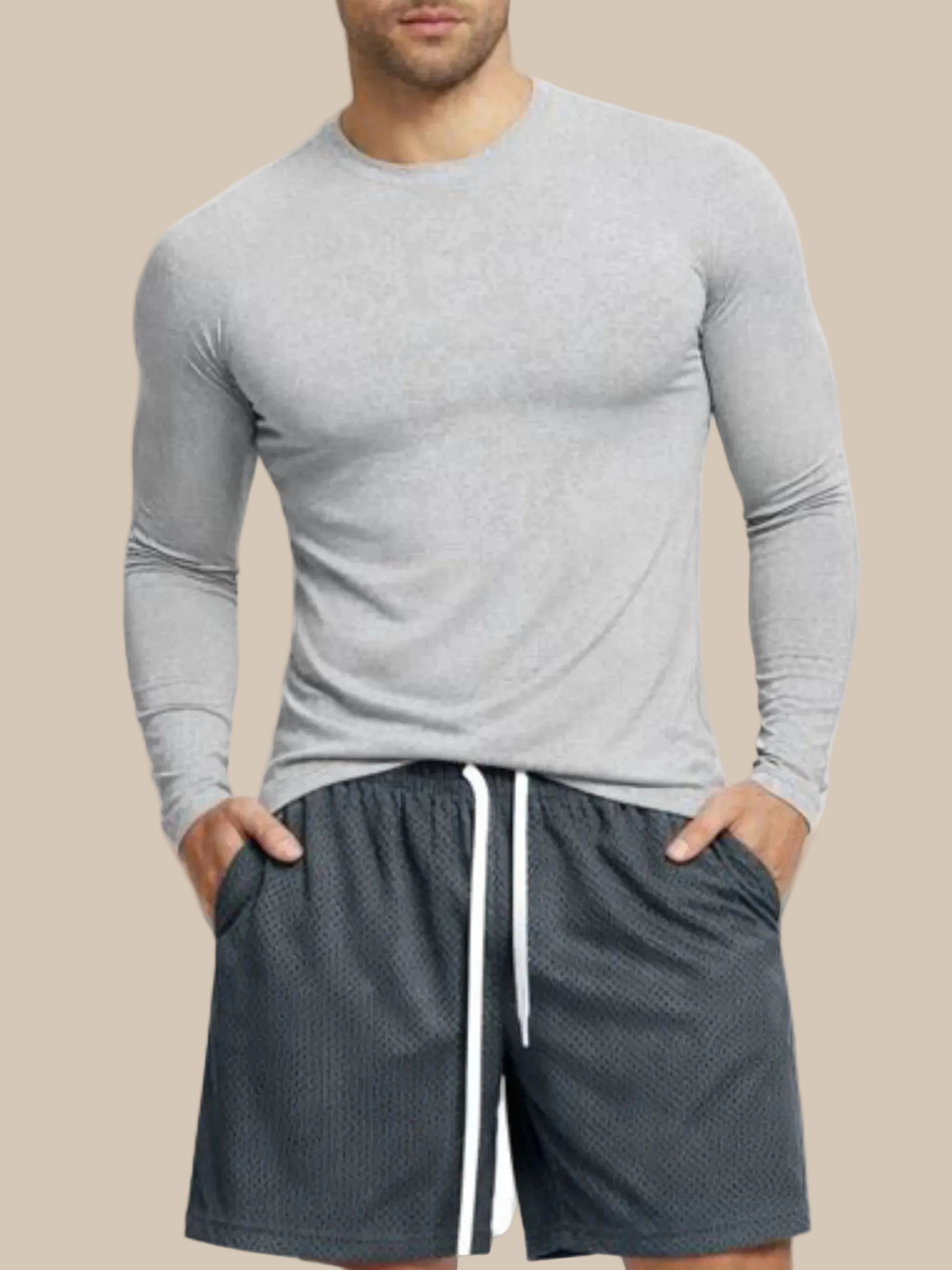 Man wearing a gray long-sleeve shirt and dark shorts on a white background