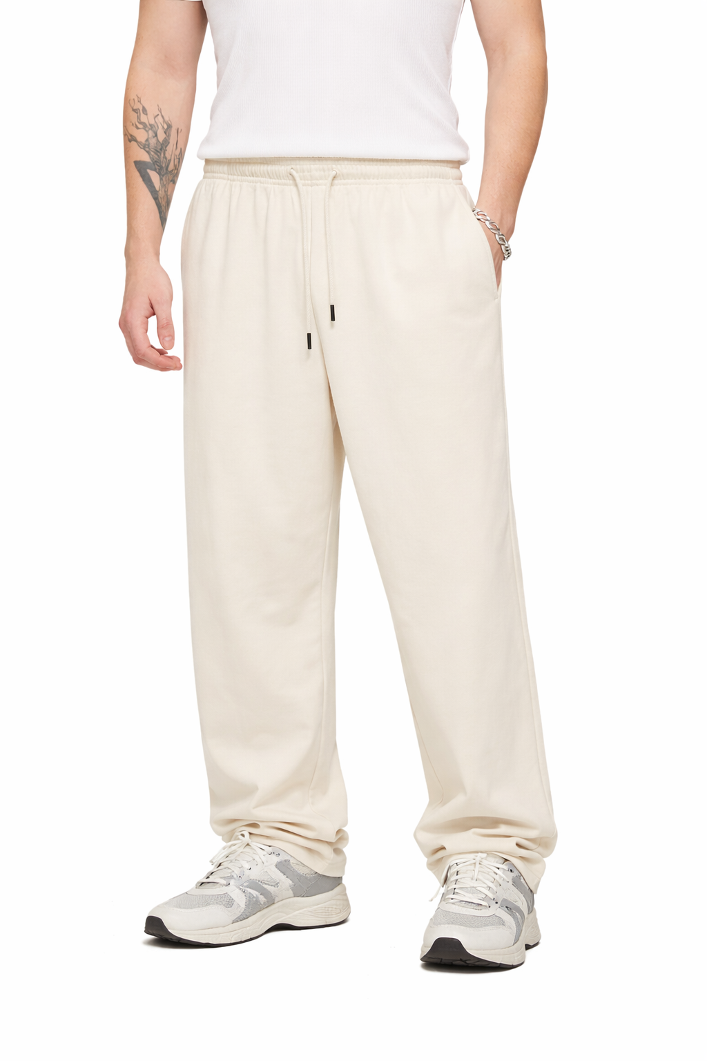 Person wearing cream-colored pants and white sneakers on a white background