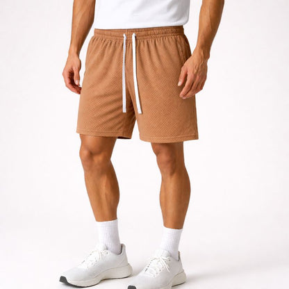 lower half of male model wearing brown drawstring shorts on a white background. 