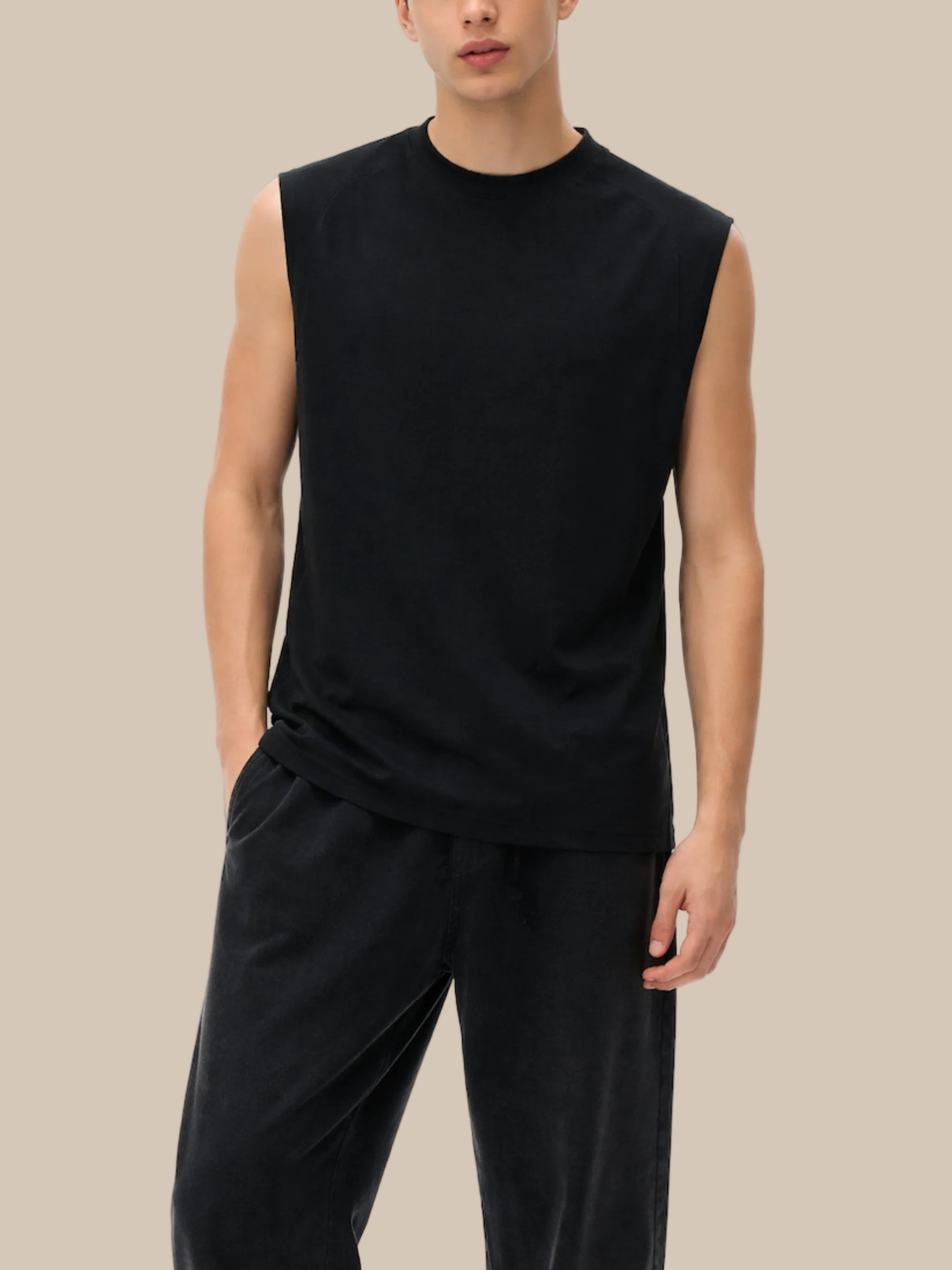 Person wearing a black sleeveless top and black pants on a white background