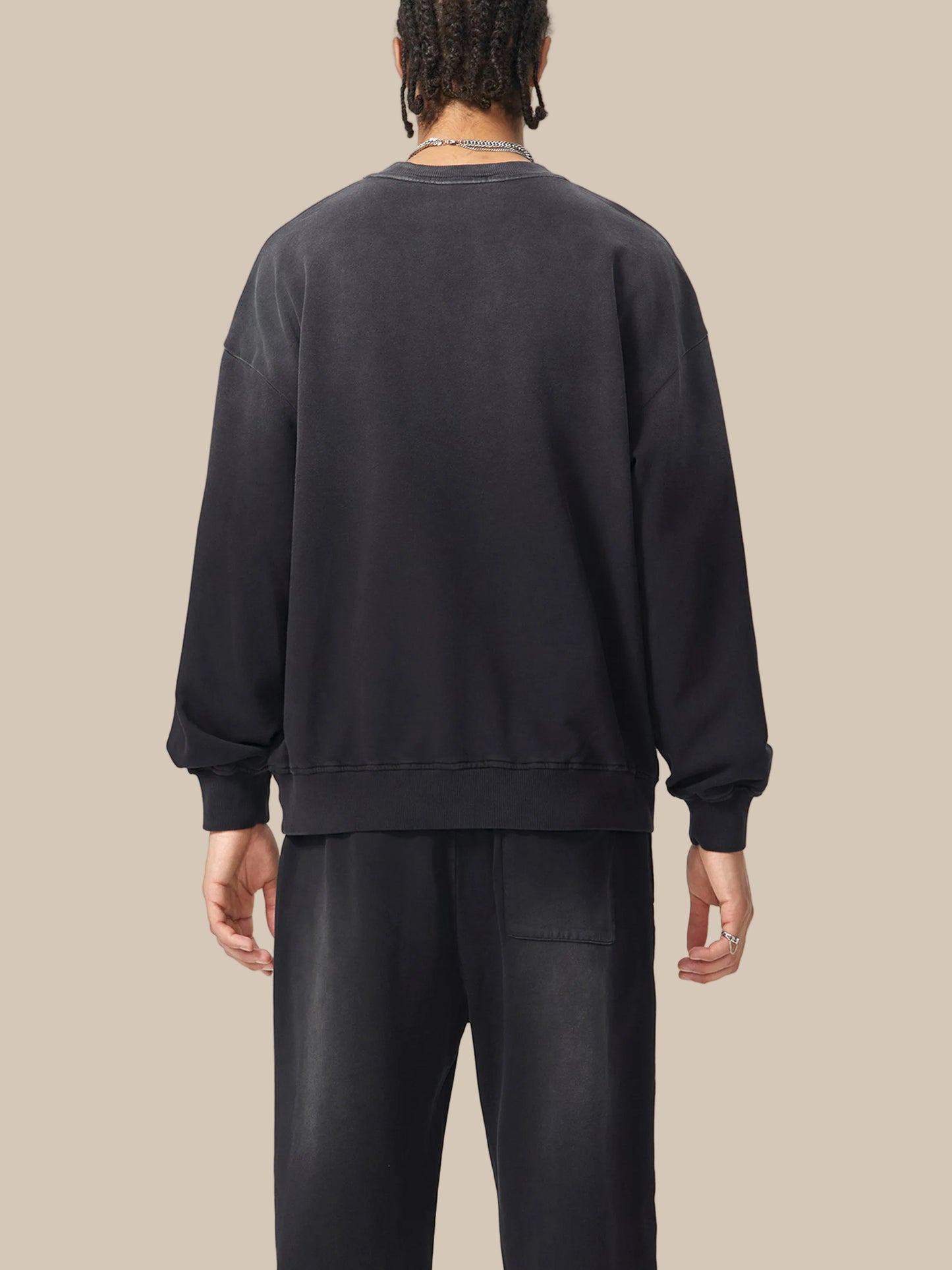 Person wearing a black sweatshirt and pants on a white background