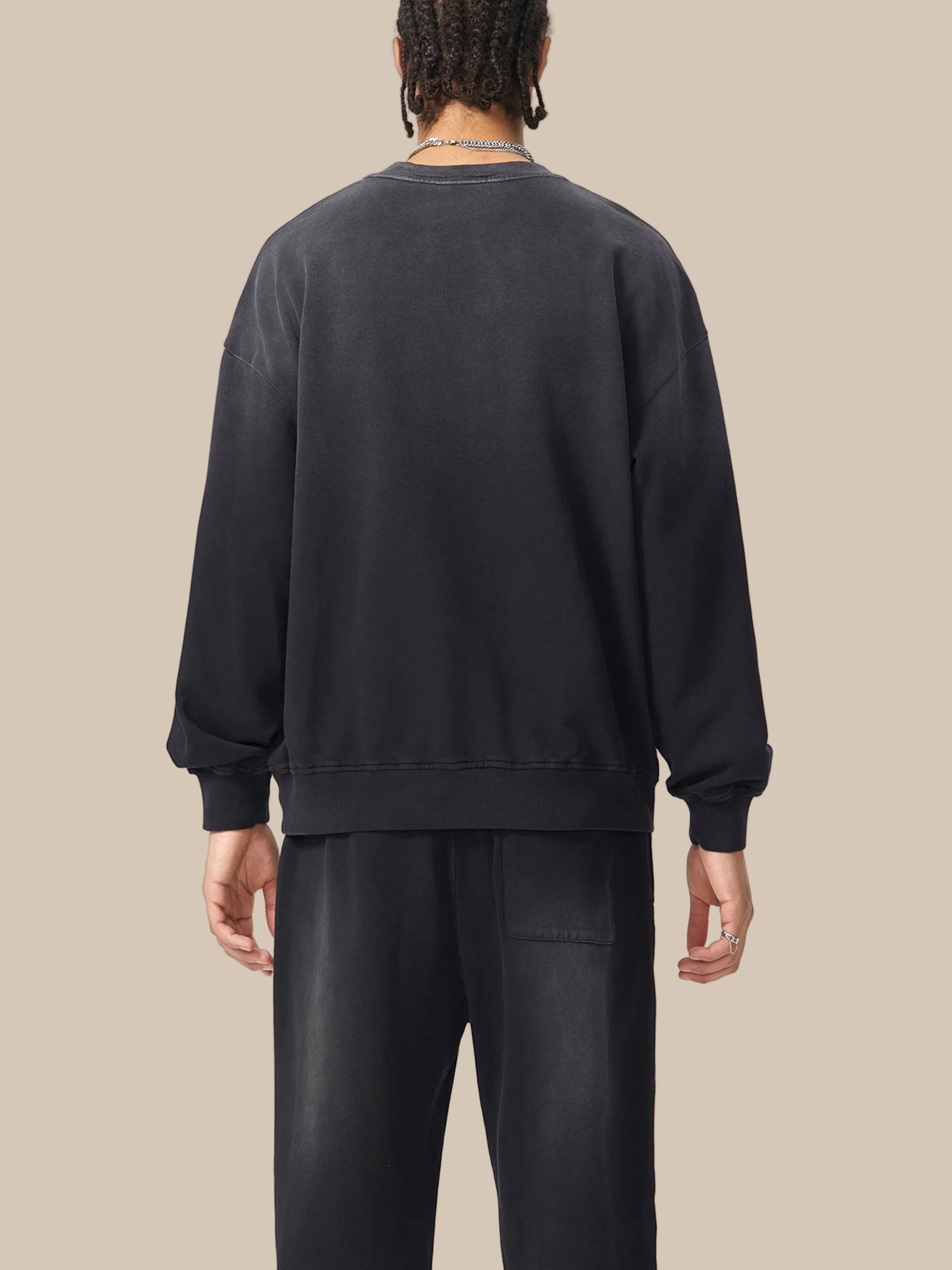 Person wearing a black sweatshirt and pants on a white background