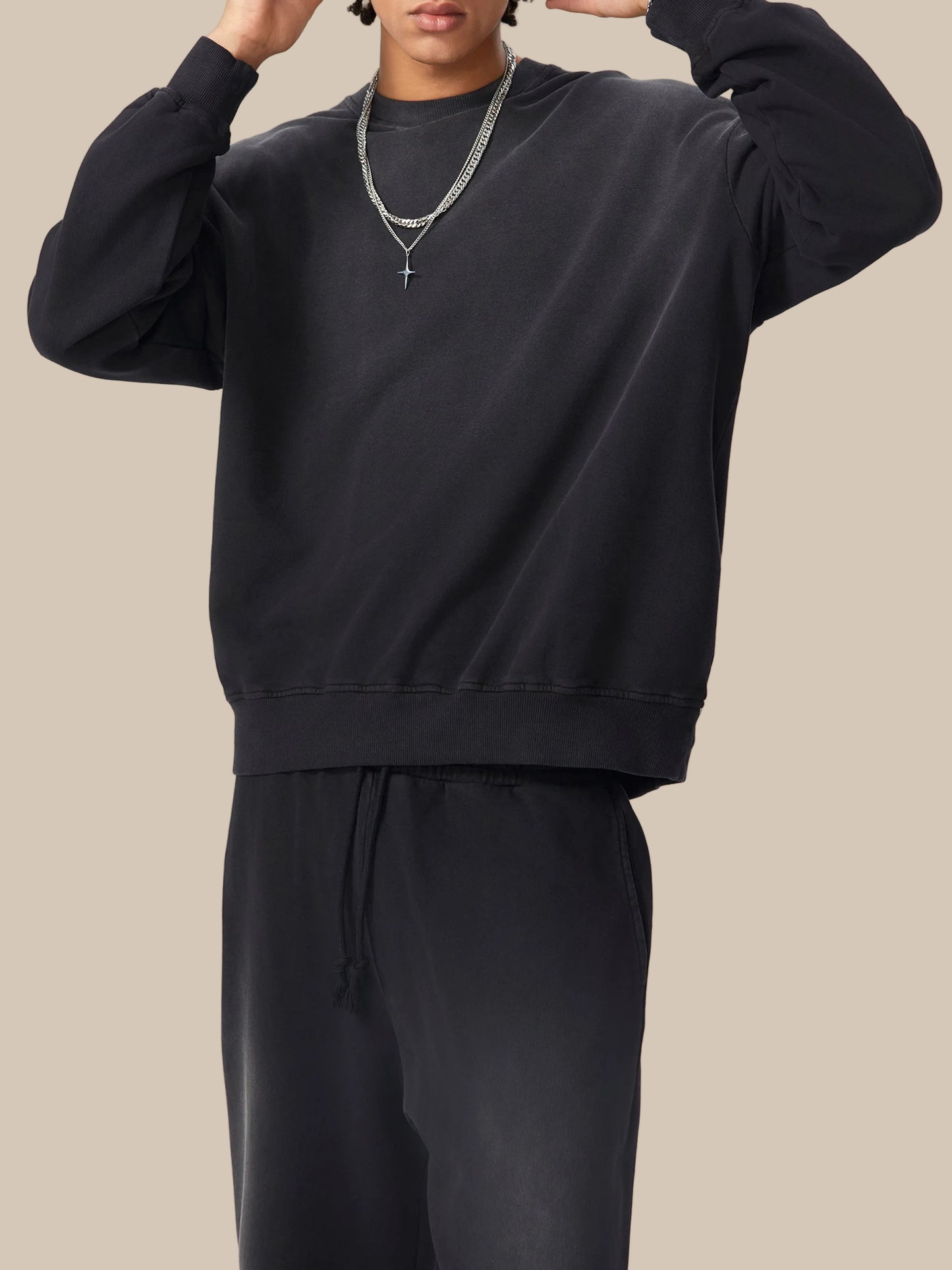 Person wearing a black sweatshirt and pants on a white background