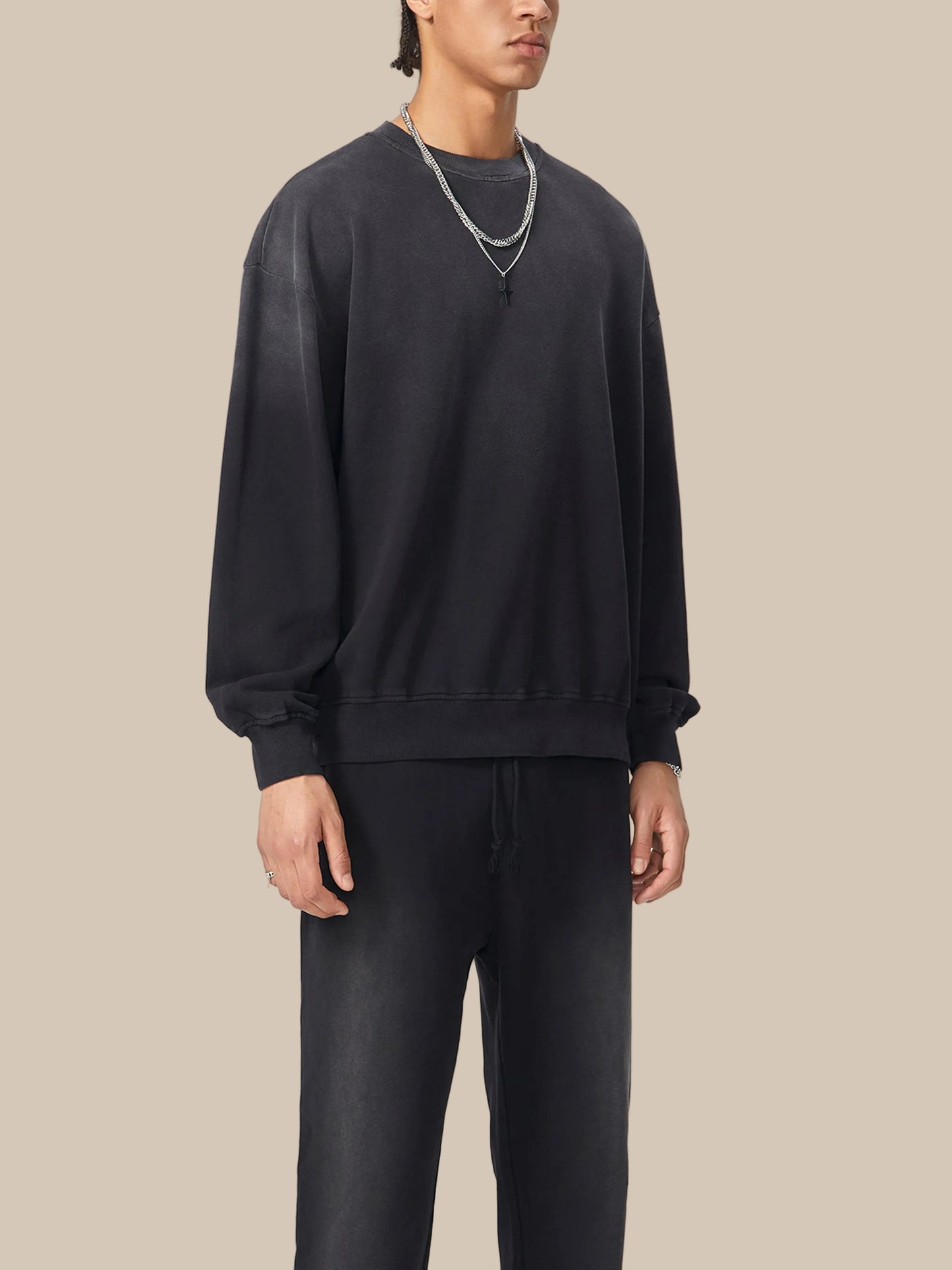 Person wearing a black sweatshirt and pants on a white background