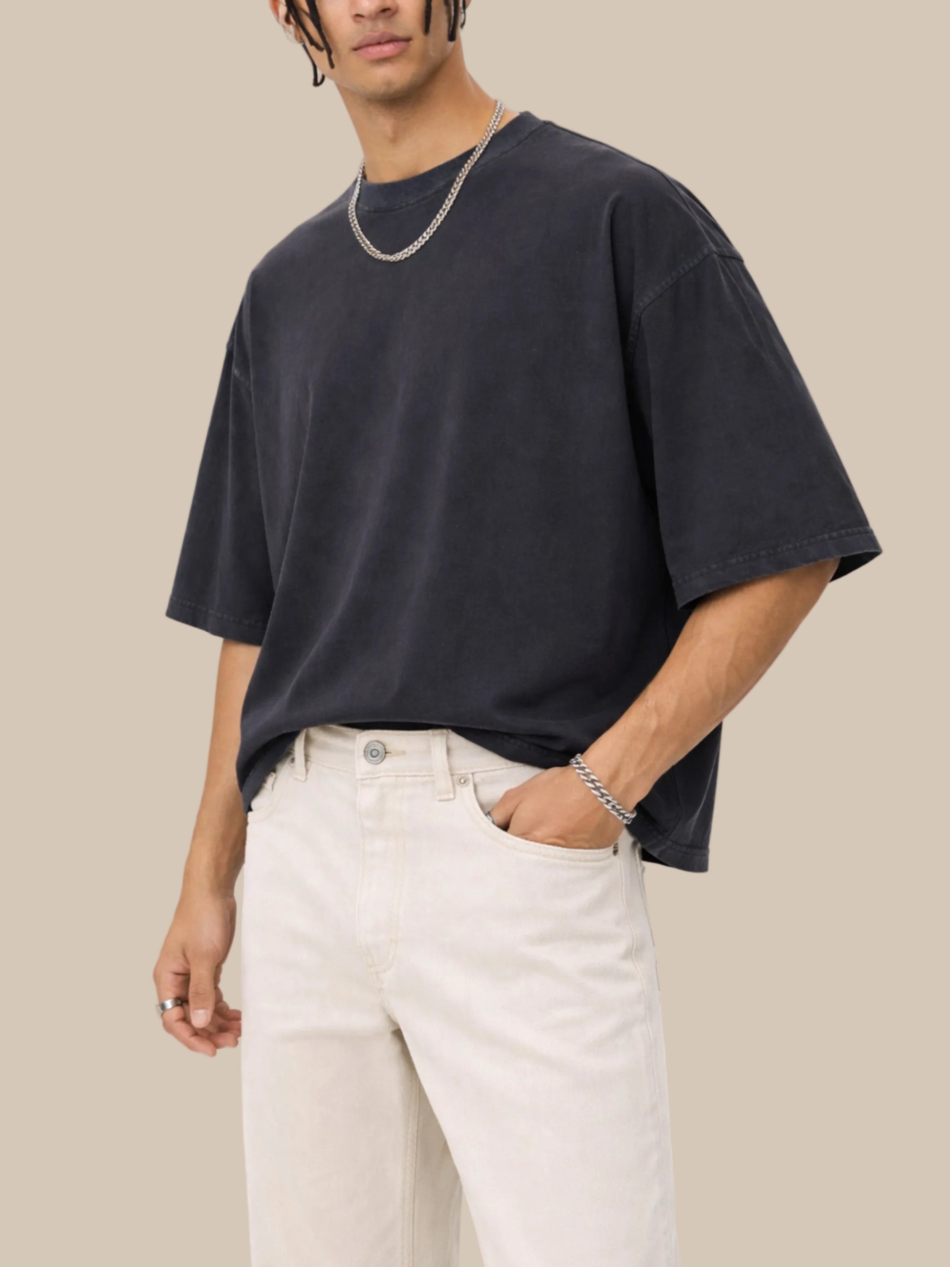 Person wearing a black oversized t-shirt and light-colored pants on a white background
