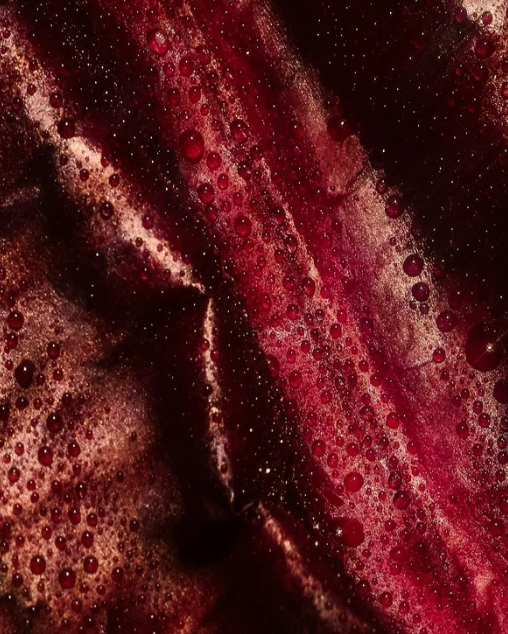 Macro texture of deep red berry extract and mica shimmer in skincare cream