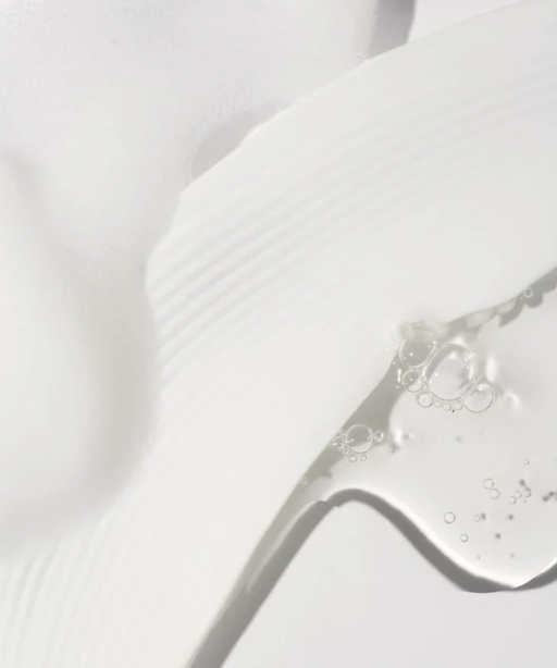 Close-up of a dropper with clear liquid on a light gray background