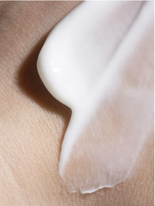 Close-up of a hand applying a white cream to skin