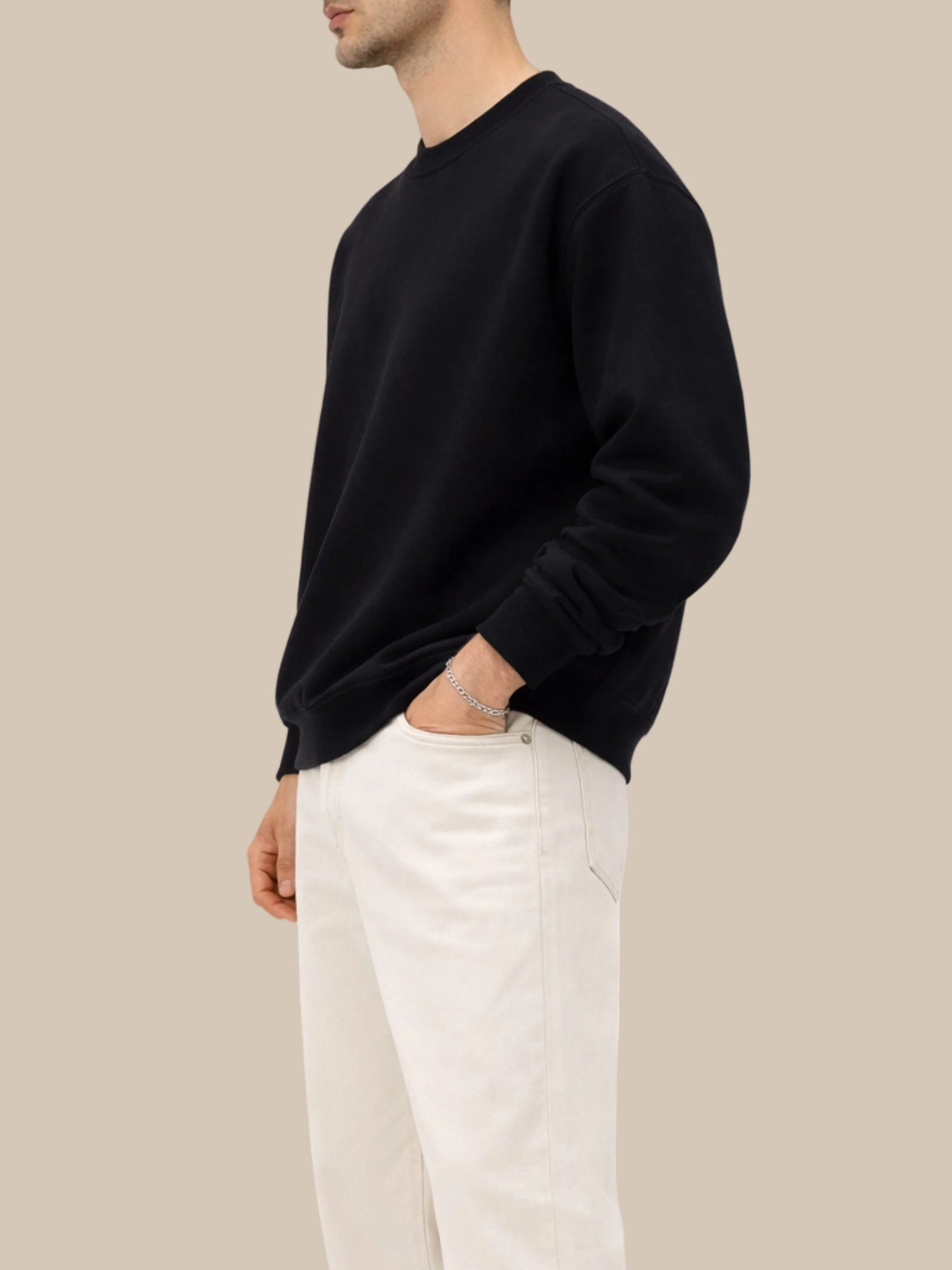 person wearing a black sweatshirt with beige jeans side view on a white background 