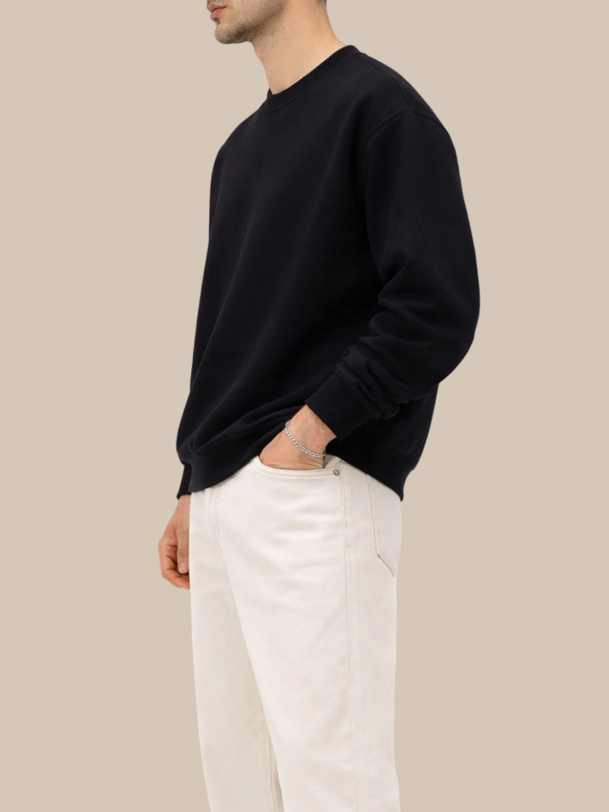 person wearing a black sweatshirt with beige jeans side view on a white background 