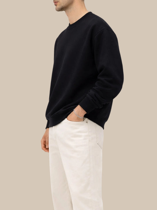 person wearing a black sweatshirt with beige jeans side view on a white background 