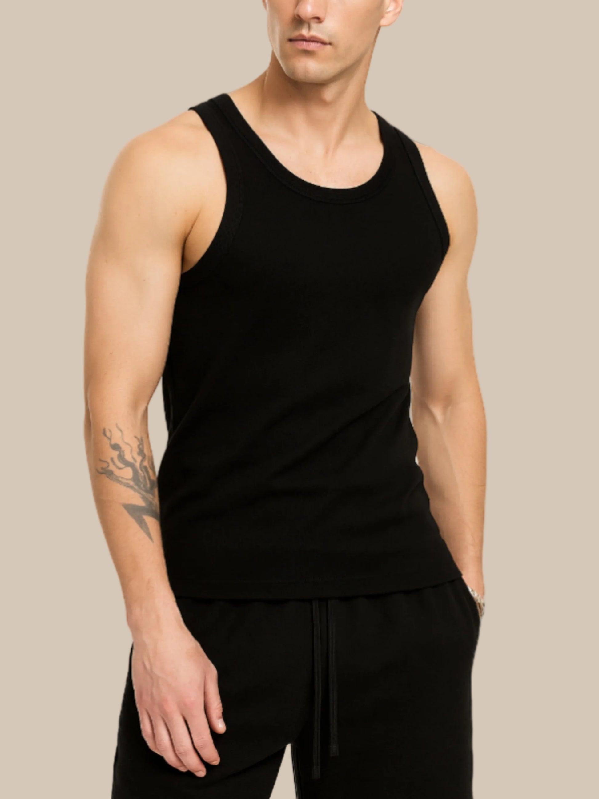 Man wearing a black tank top and black pants on a white background