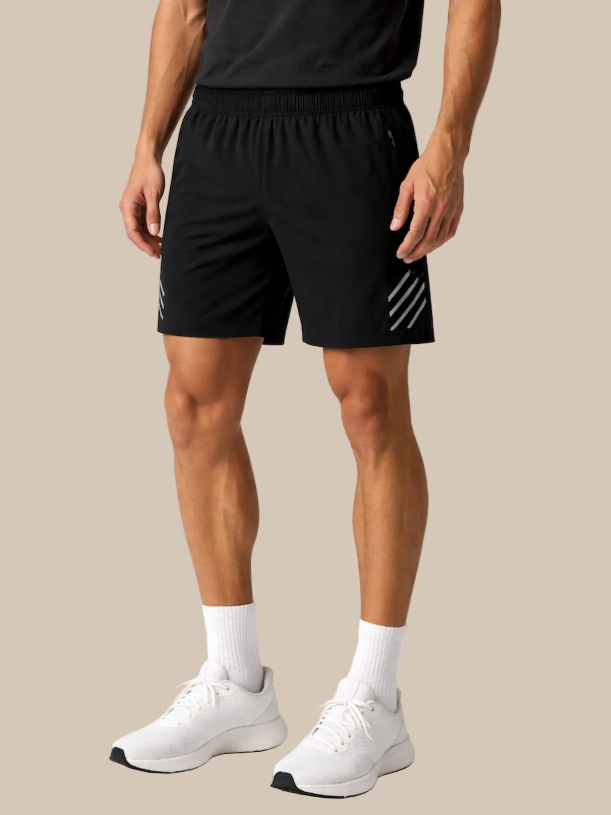 Person wearing black athletic shorts with white stripes on a white background