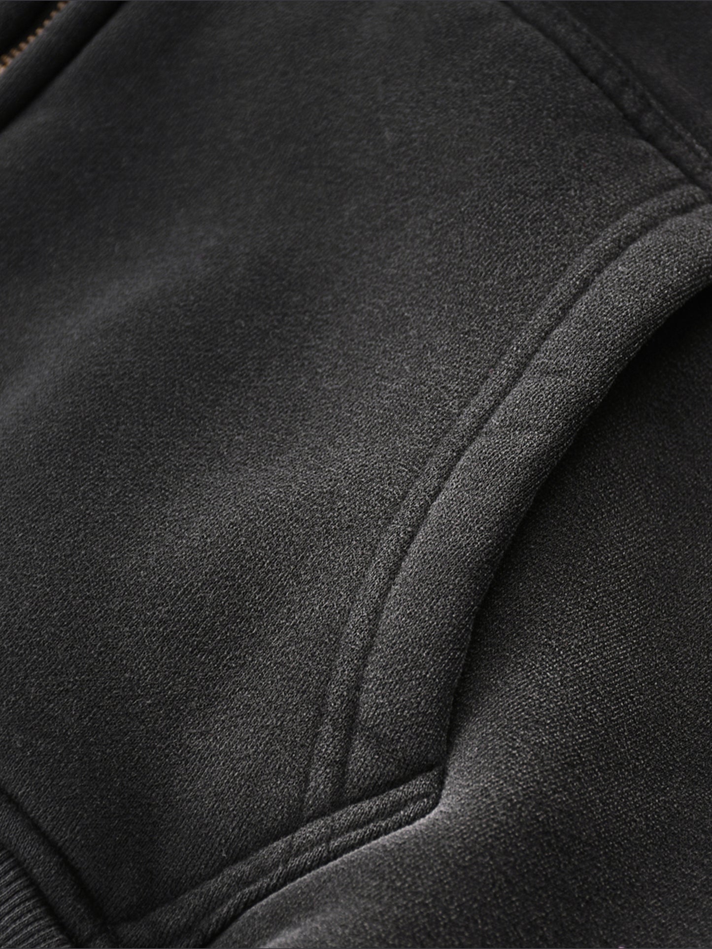 Close-up of a black jacket with a focus on texture, pocket,  and stitching detail.