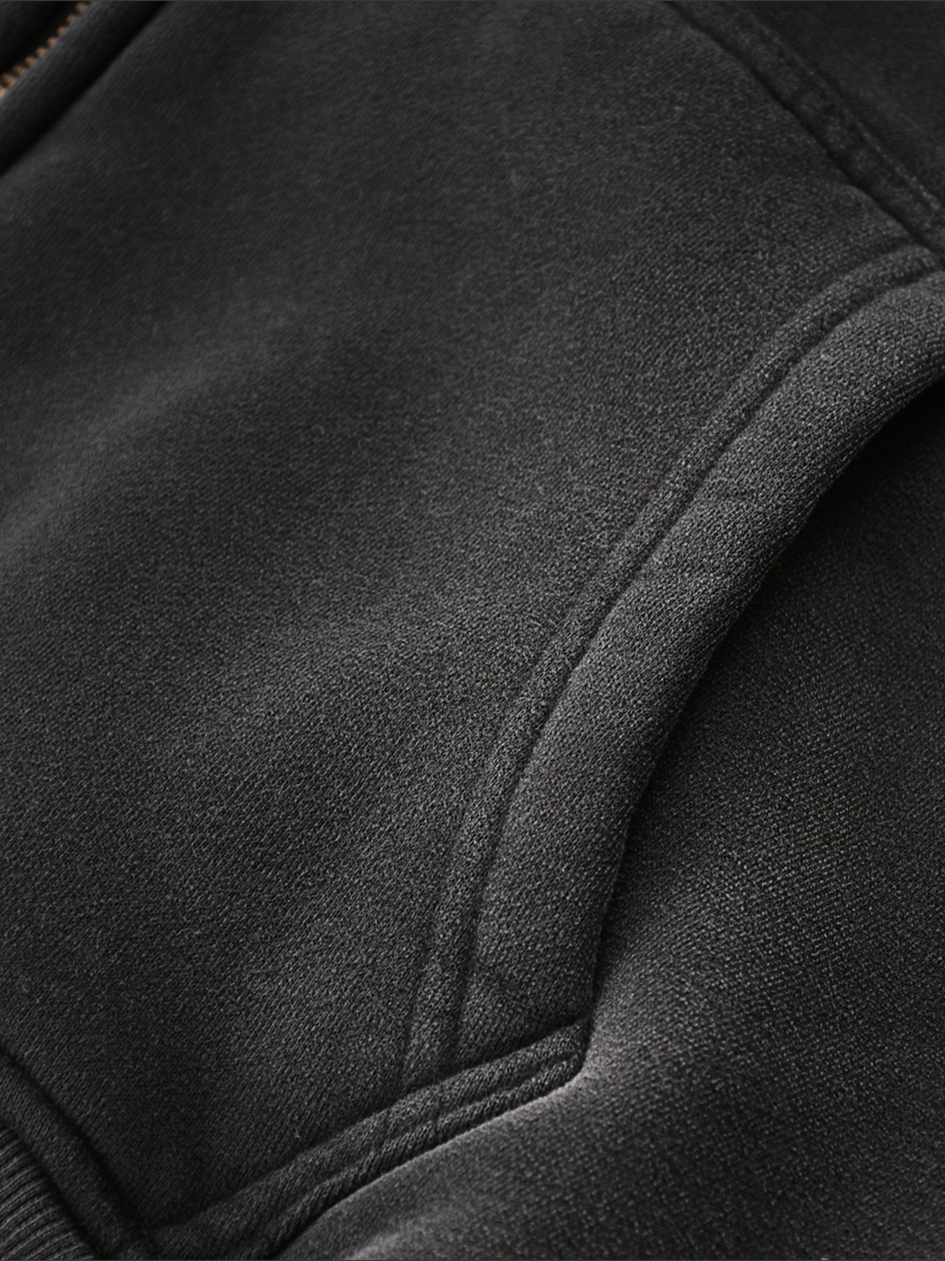 Close-up of a black jacket with a focus on texture, pocket,  and stitching detail.
