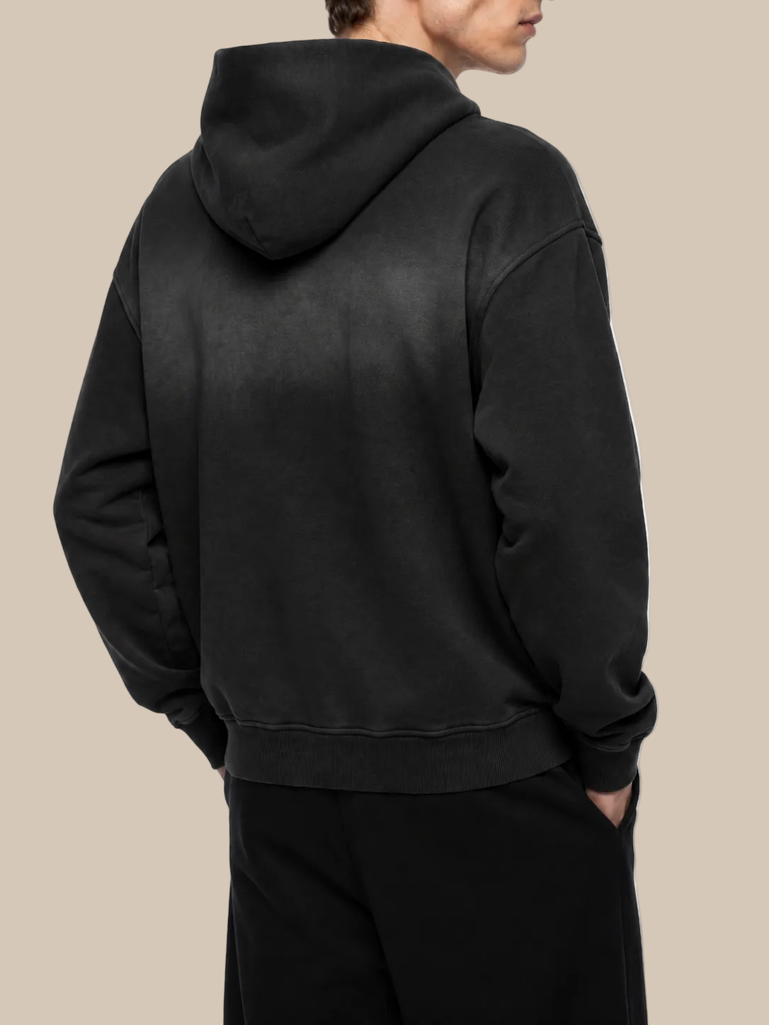 Person wearing a black hoodie from behind on a white background