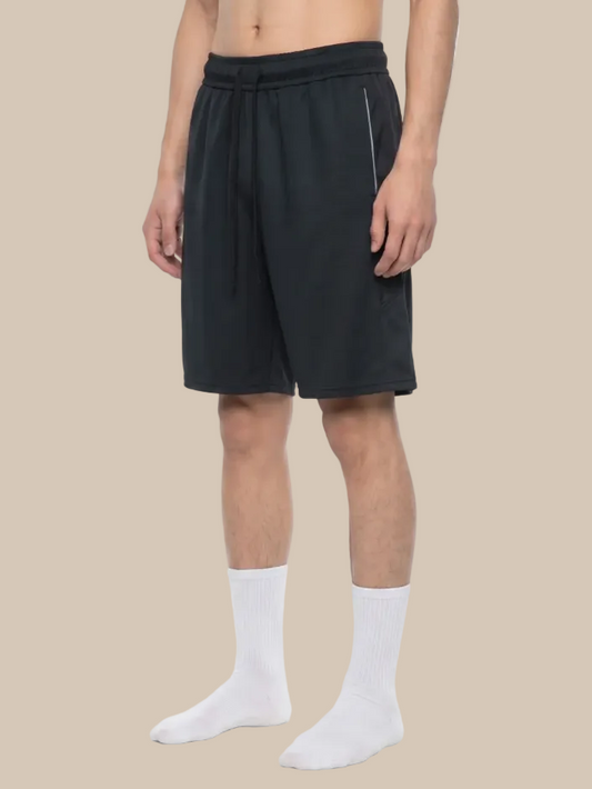 Model wearing kinetic shorts above the knee in black on a beige background 