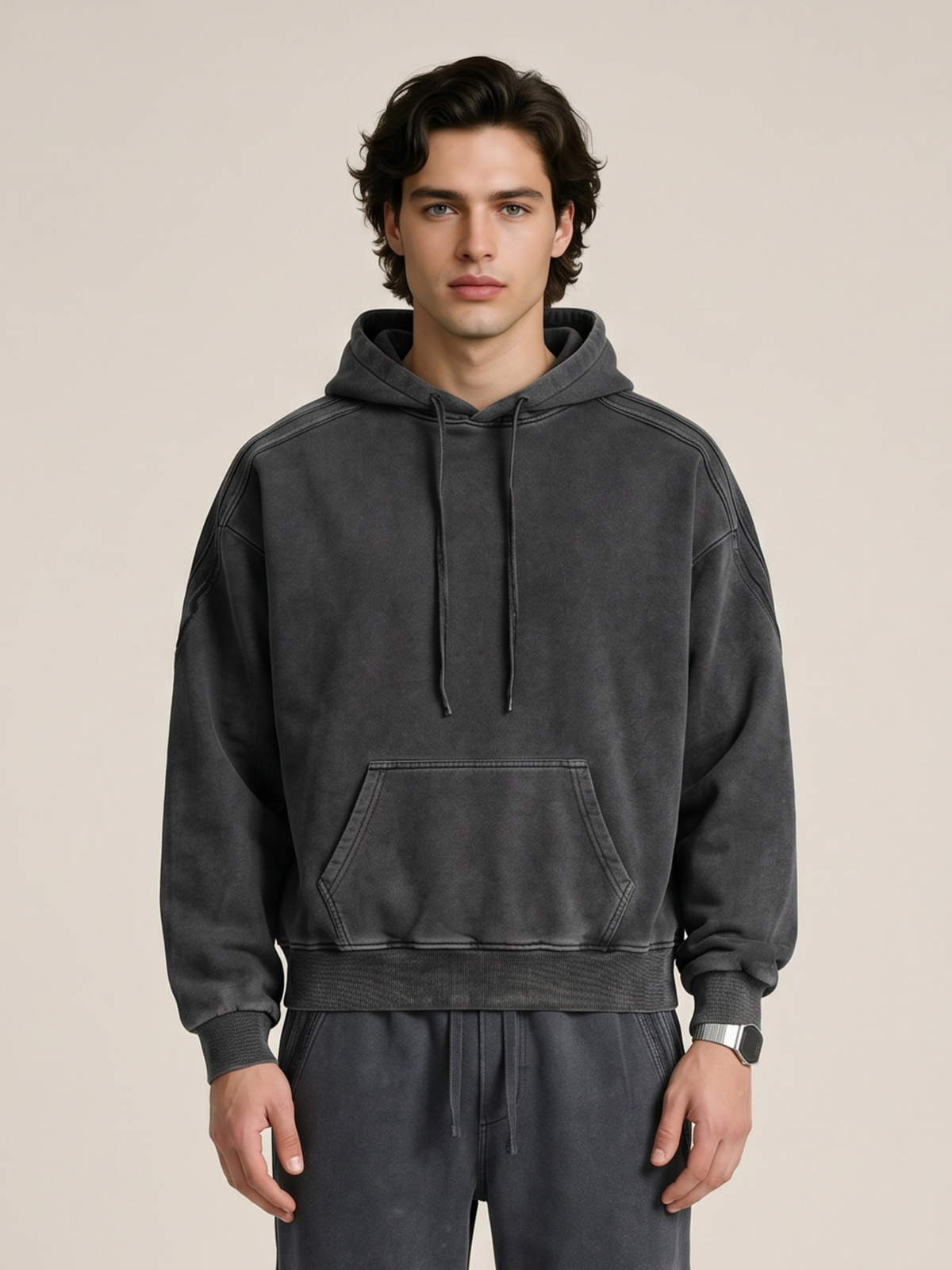 A model wearing a sun bleached deconstructed black hoodie with matching sweatpants on a beige background. 