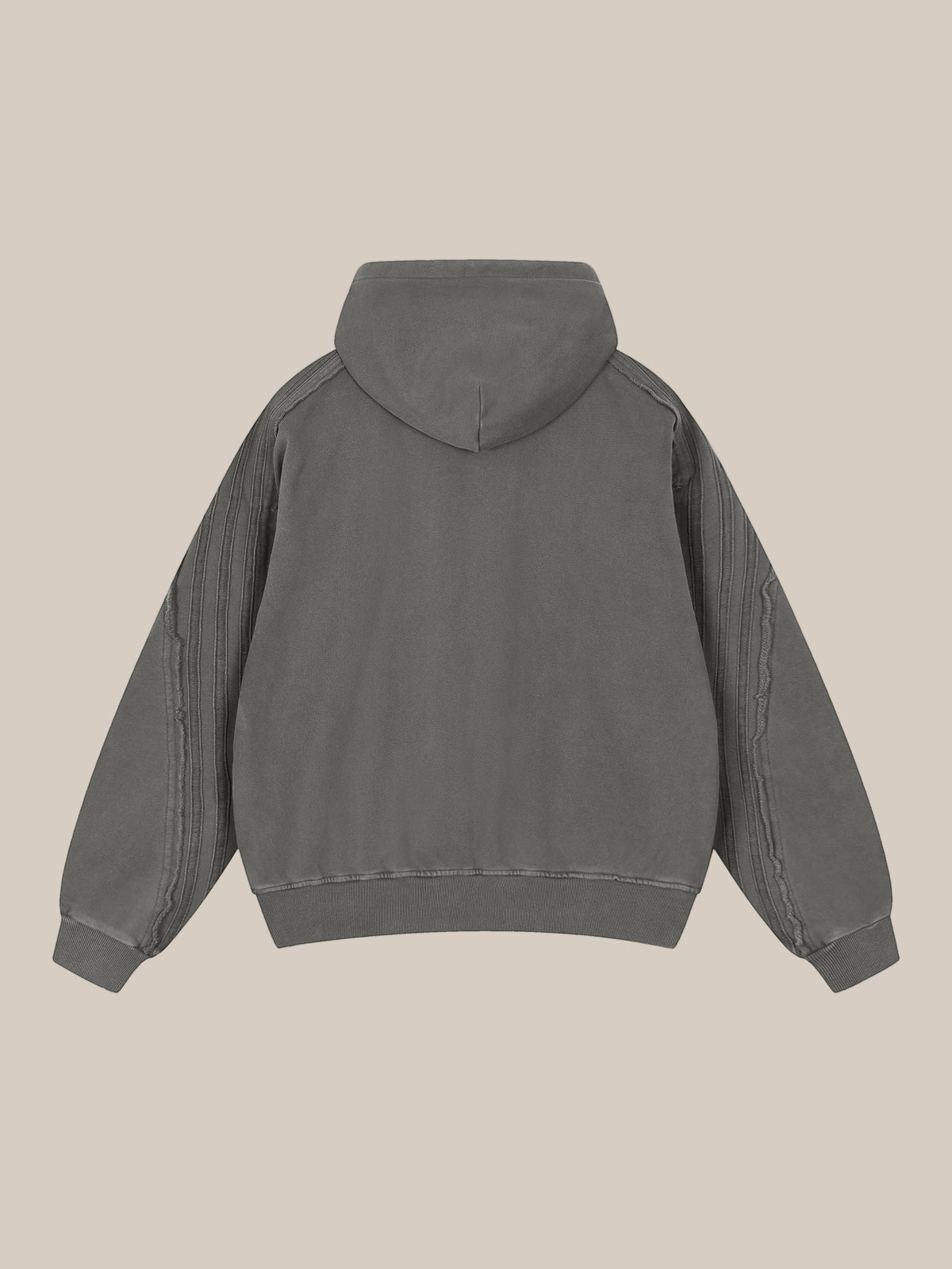 Backside flat lay of a sun bleached deconstructed dark gray hoodie on a beige background. 