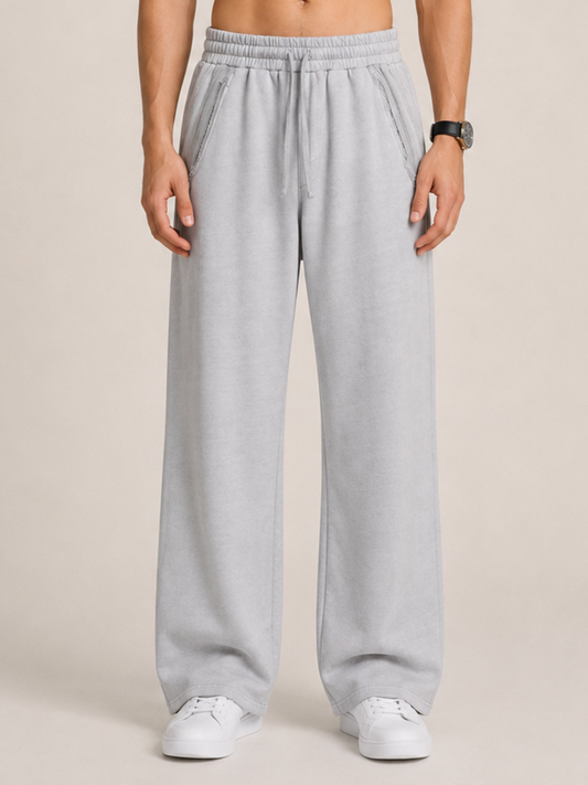 close-up of a model wearing a pair of light gray sweatpants on a beige background. 