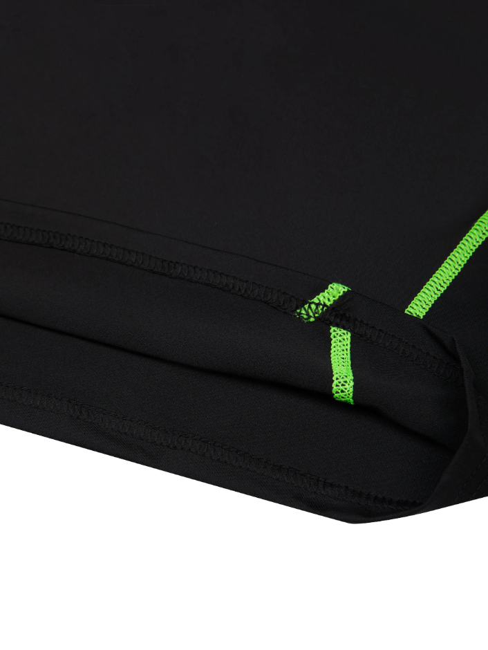 Up close image of the hem of the training shirt in black with green accents on a white background. 