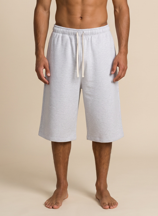 A man wearing light heather gray drawstring shorts, shown from the waist down against a plain beige studio background.