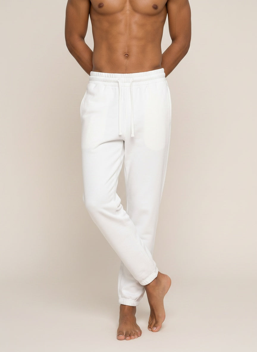 White sweatpants worn by a shirtless male model, shown from the waist down against a plain beige studio background.