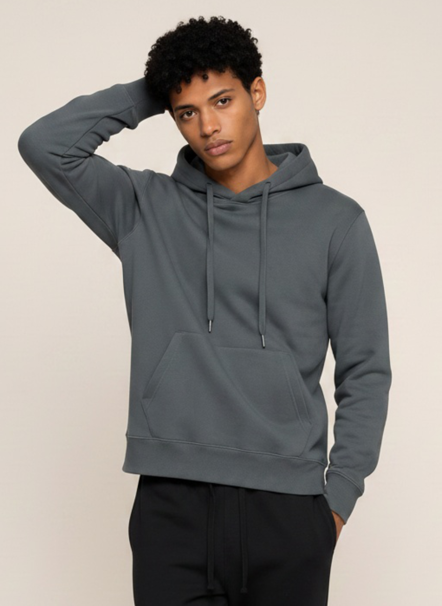 A man wearing a dark gray pullover hoodie with a front kangaroo pocket and matching drawstrings, paired with black sweatpants, against a plain light beige background.