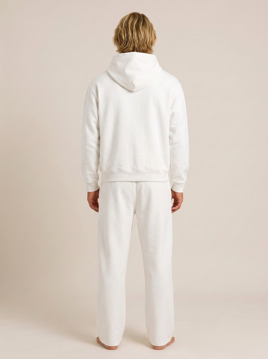 A model viewed from the back wearing a matching white hooded sweatshirt and wide-leg sweatpants set against a solid light beige studio background.