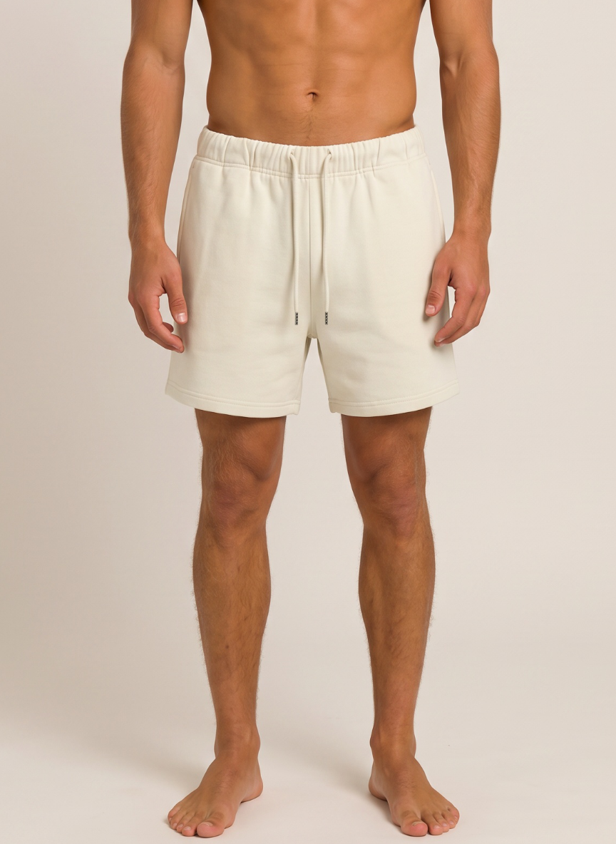 A man wearing off-white drawstring shorts, shown from the waist down against a plain beige studio background.