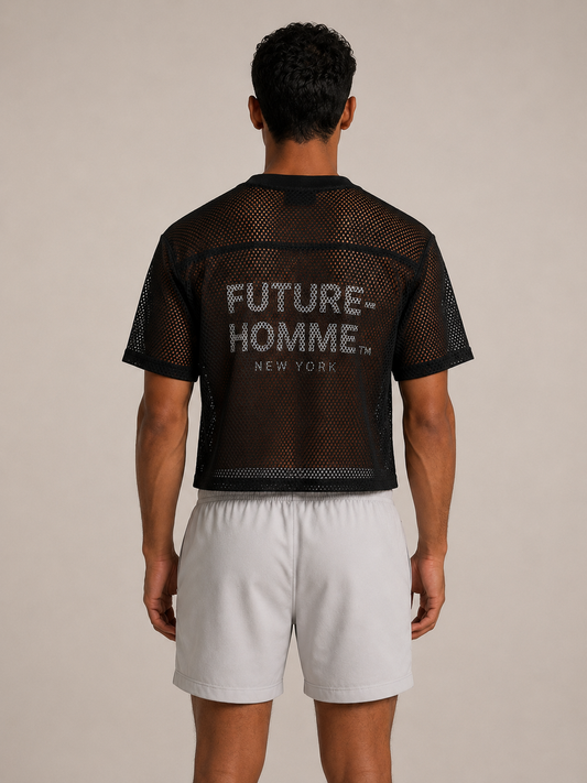 A man viewed from the back wearing a black mesh short-sleeve crop top with 'FUTURE-HOMME NEW YORK' printed in white on the back, paired with light gray shorts, against a plain beige studio background.