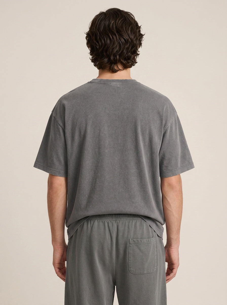 A man in side profile wearing light beige drawstring lounge pants, standing barefoot against a solid beige studio background.