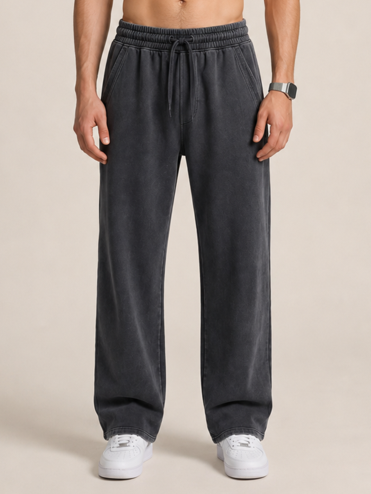 close-up of a model wearing a pair of black sweatpants on a beige background. 