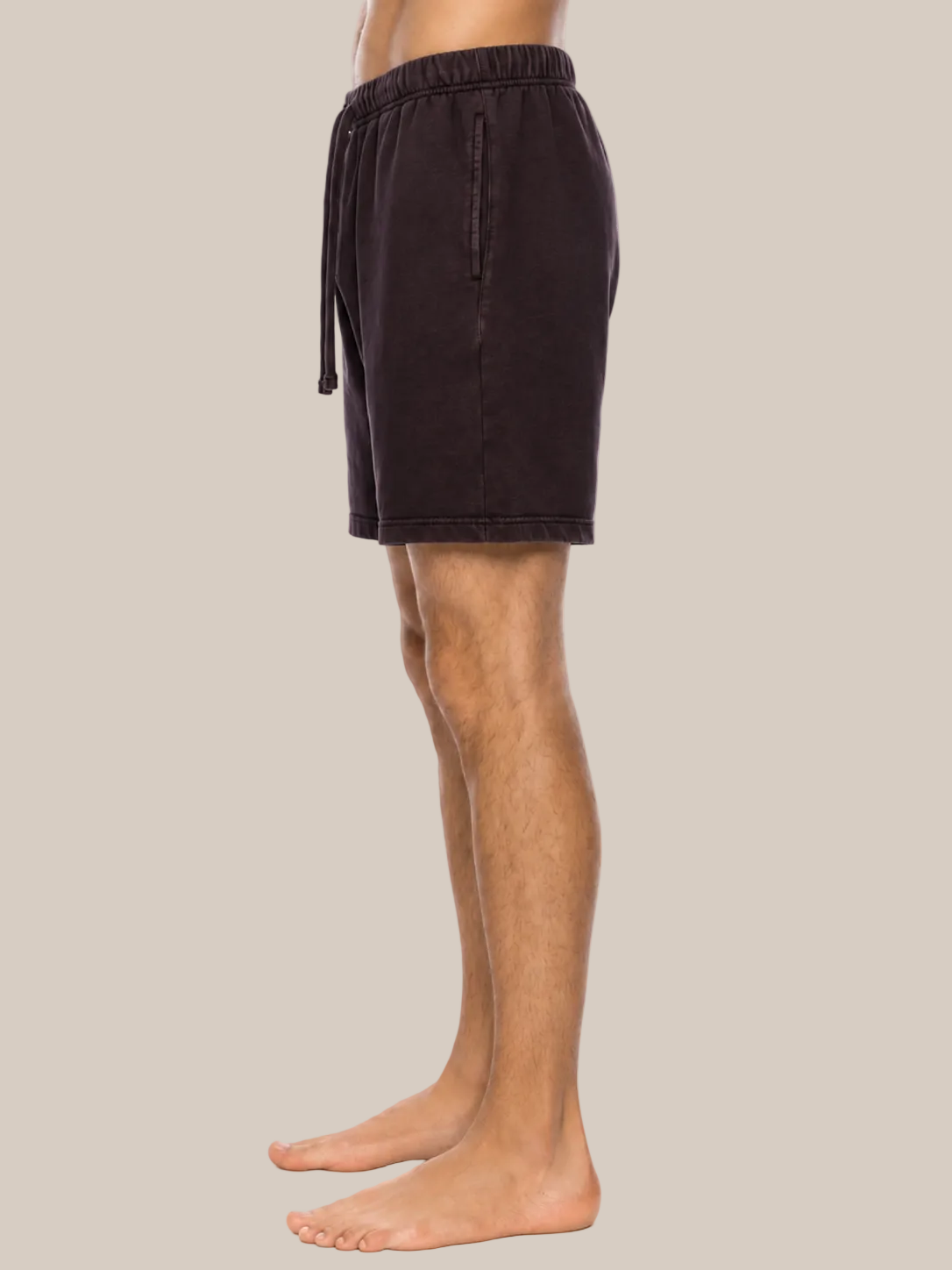 Side view of a person wearing dark brown drawstring shorts against a plain white background.