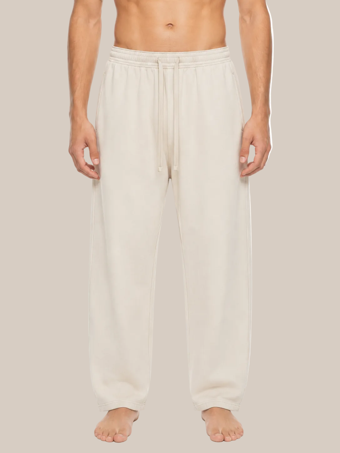A man wearing light beige drawstring sweatpants, shown from the waist down against a plain white background.